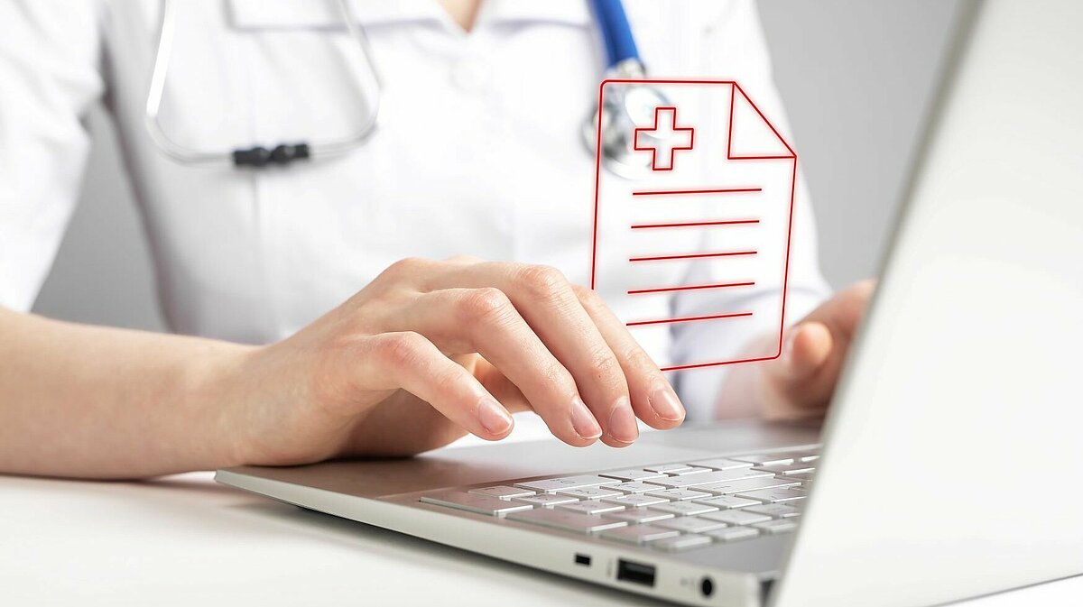 Ärztin sitzt am Laptop und lädt Dokumente hoch